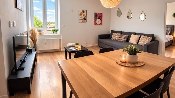 Una sala de estar moderna con un sofá, una mesa de comedor de madera y un mueble para televisión.
