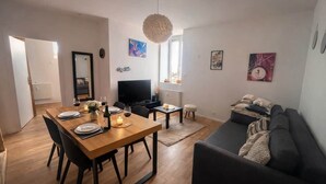 Una sala moderna con comedor, un sofá y una televisión.