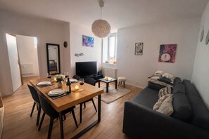 Ein modernes Wohnzimmer mit Essbereich, einer Couch und einem Fernseher.