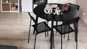 Ett modernt kök med vita skåp, en mikrovågsugn, en vattenkokare och ett soffbord med en skylt som visar texten ”Café”.