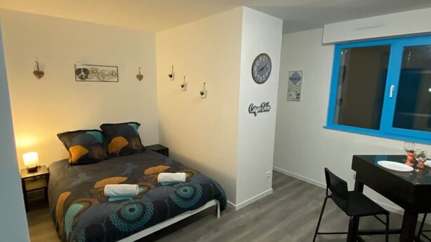 Une chambre à coucher avec un lit, une table de chevet et une fenêtre.