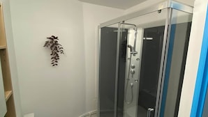 Une salle de bain moderne dotée d’une douche à parois de verre, de toilettes et d’un lavabo.