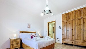 Ein Schlafzimmer mit einem hölzernen Bett, Nachttischen, einem Kleiderschrank und einer Deckenleuchte.