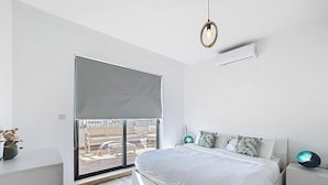 A modern bedroom with a large bed, a sliding glass door to a balcony, a ceiling fan, and a wall-mounted air conditioner. - Mosta Couples Retreat - Sunny Rooftop 2BR (Il-Mosta)