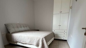 Ein Schlafzimmer mit einem Bett, einem Kleiderschrank und Fliesenboden.