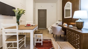 A compact living space with a dining area, a seating area, a TV, and a mirror. - Epidavros Villas - Rodia Garden Retreat (Epidaurus)