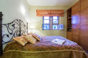A bedroom with a bed, a window with curtains, a bedside table, and a wardrobe. - Epidavros Villas - Elia Garden Retreat w Pool (Epidaurus)