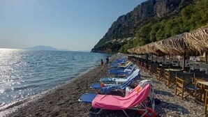 A beach with sun loungers and umbrellas, a rocky shoreline, and a mountain in the background. - Epidavros Villas - Voukamvilia Retreat w Pool (Epidaurus)