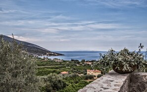 A coastal landscape with a stone wall, olive trees, and a distant view of the sea. - Epidavros Villas Thymari Garden Seaview Retreat (Epidaurus)