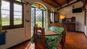 Una habitación con mesa de comedor, sillas, cama, ventana con vistas y un candelabro.