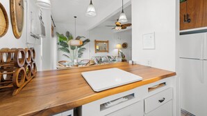 A kitchen with a wooden countertop, white cabinets, and pendant lights. - Kona Mansions#B217 2nd Floor, Beautiful unit/Ocean views & Air Conditioning (Kailua Kona)