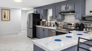Una cocina moderna con armarios grises, un refrigerador negro, un horno integrado y una isla de mármol con detalles azules.