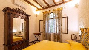 A bedroom with a large mirror, a bed with yellow bedding, a small table, and a chair. - Apartment 'Tenuta Donna Vittoria Mandarino' with Mountain View, Wi-Fi and Air Conditioning (Trapani)