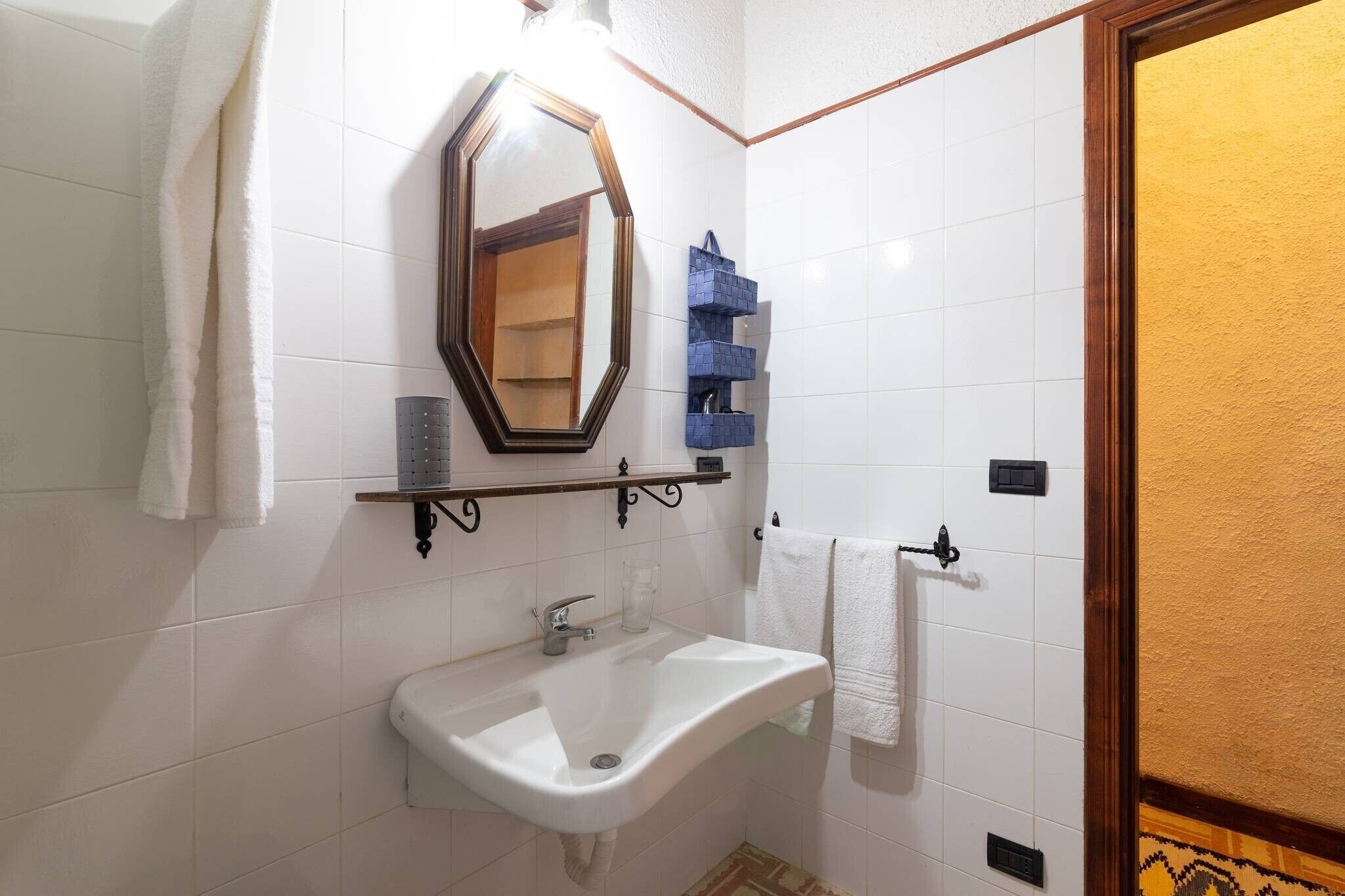 Une salle de bain avec un lavabo blanc, un miroir et un porte-serviettes.