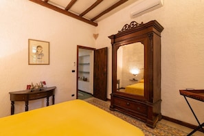 A room with a bed, a wooden dresser, a mirror, a small table, and a framed picture on the wall.