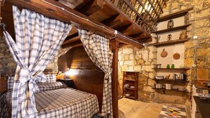 A rustic bedroom with a wooden ceiling, a bed with plaid curtains, a stone wall, and a shelf with kitchenware. - Apartment 'Tenuta Donna Vittoria Piccola' with Mountain View, Wi-Fi and Air Conditioning (Trapani)