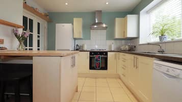 A modern kitchen with a central island, a stove, oven, and dishwasher.