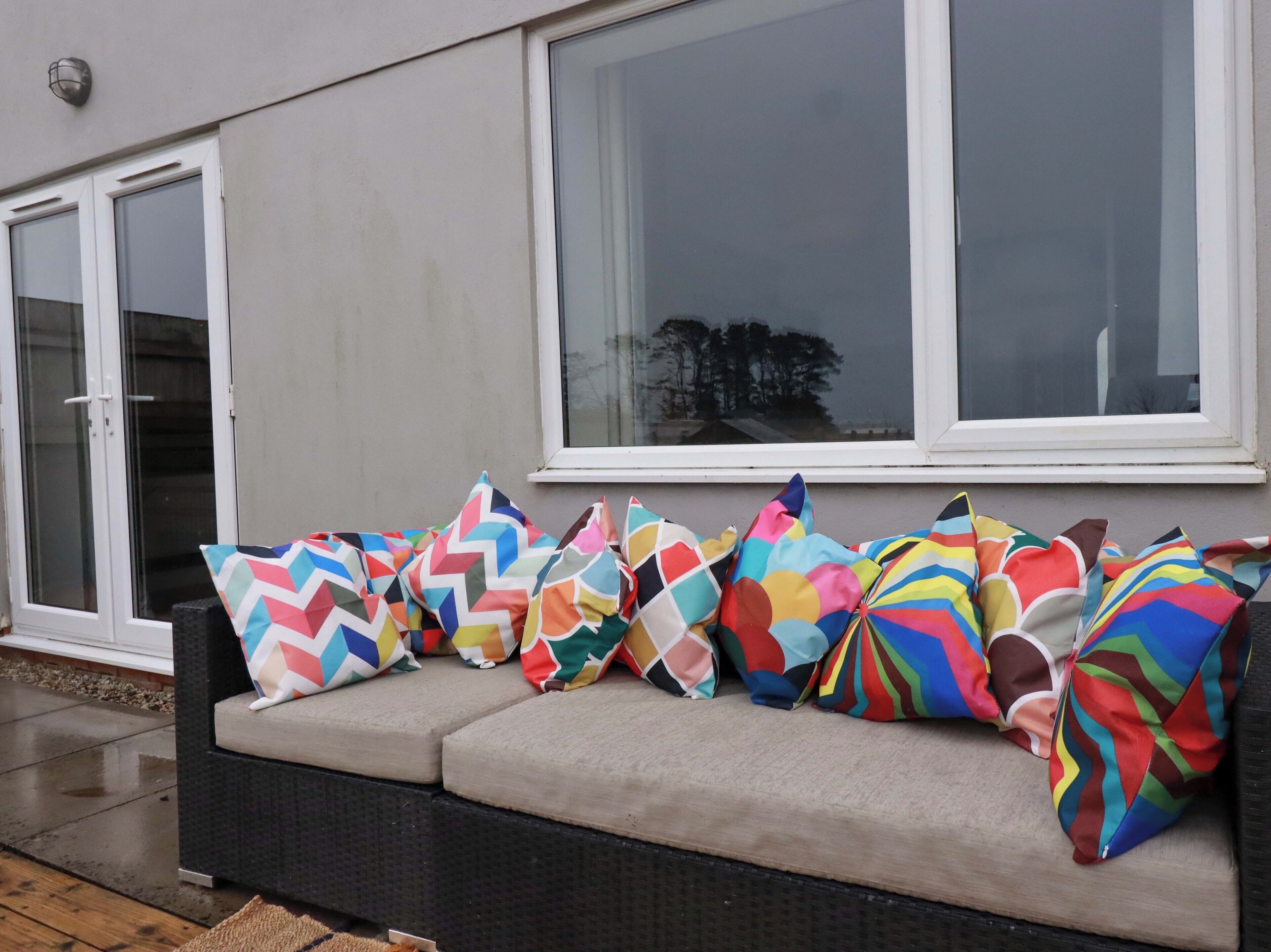 Ein Sofa mit bunten Kissen, ein Fenster und eine Tür.