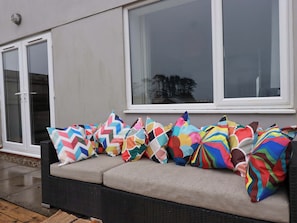 A sofa with colorful cushions, a window, and a door. - Trelowen (Wadebridge)