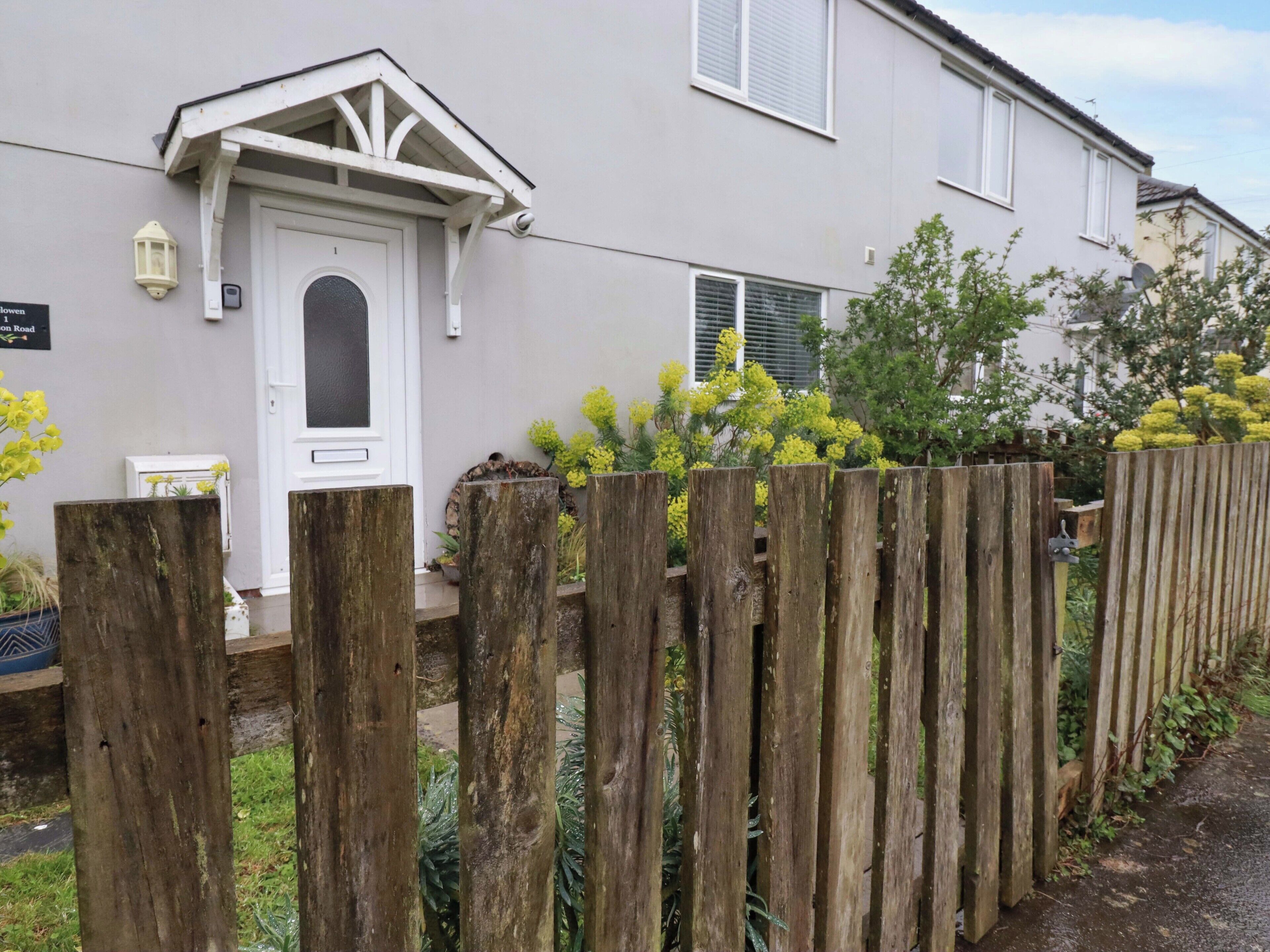 Un edificio residencial con puerta blanca, un pequeño porche y valla de madera.