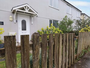 A residential building with a white door, a small porch, and a wooden fence. - Trelowen (Wadebridge)