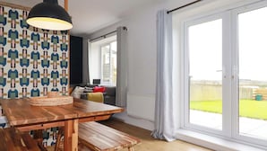 Une cuisine moderne avec une table et un banc en bois, un luminaire suspendu et un mur orné d’un motif.