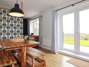 Cozinha moderna com mesa e banco de madeira, luminária pendente e parede estampada.