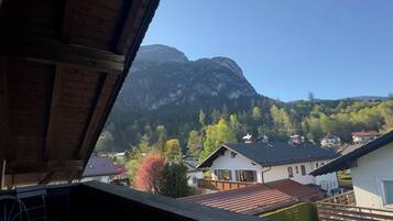 Bergblick von einem Holzhaus mit sichtbaren Häusern und blauem Himmel.