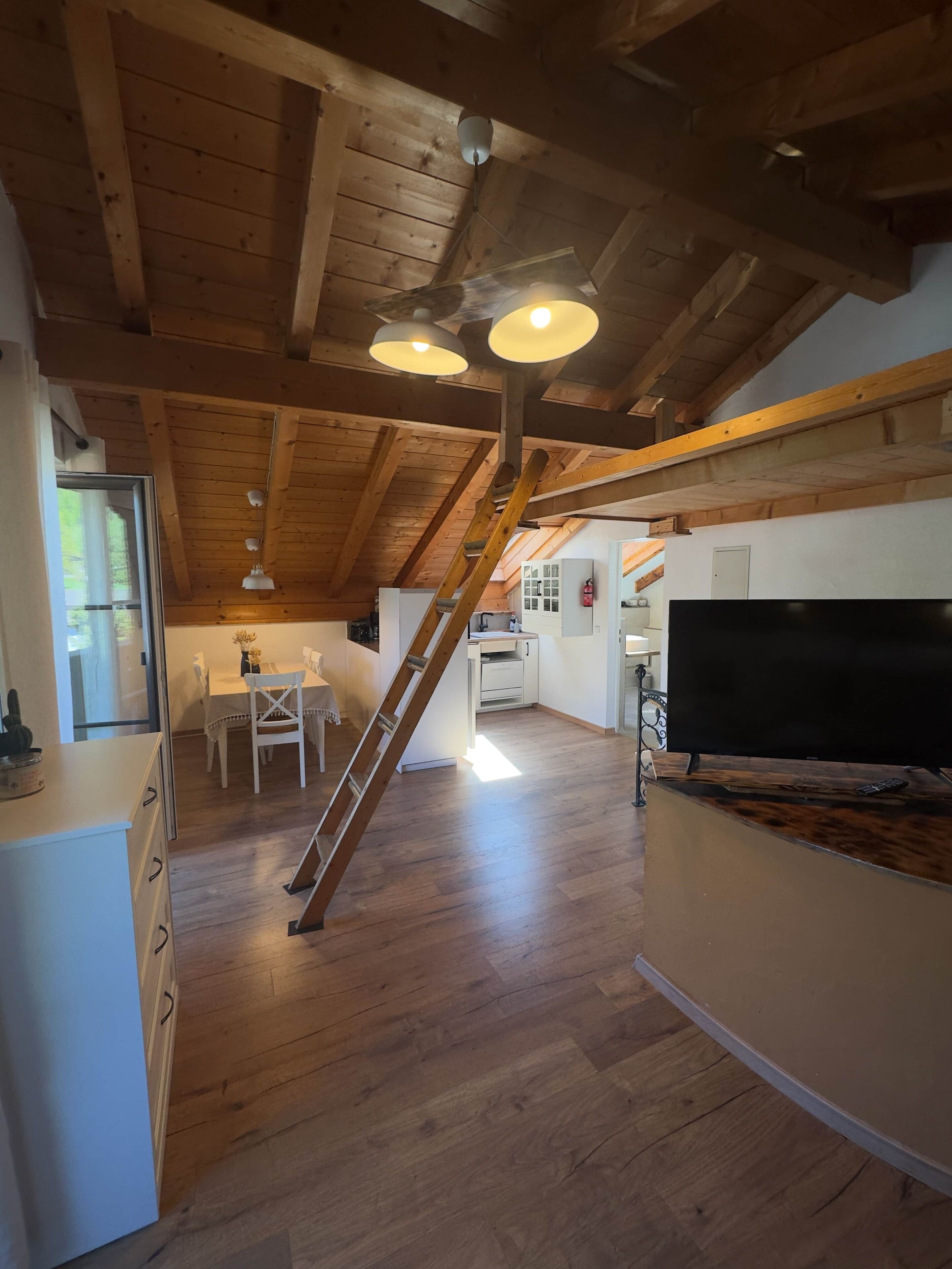 Eine geräumige Küche mit Holzbalken, einem Essbereich und einem großen Fernseher.