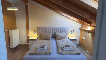 Ein Schlafzimmer mit einem großen Bett, Holzbalkendecke, Nachttischlampen und einer Heizung.