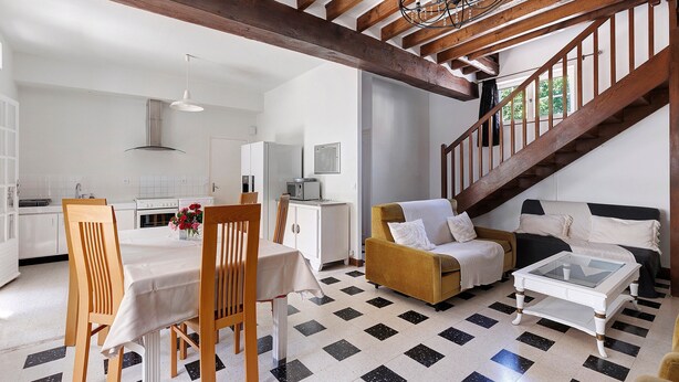 Un vaste espace de vie comprenant une table à manger, des chaises, un canapé et un escalier.
