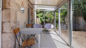 Une terrasse avec une table et des chaises, un miroir suspendu et une vue sur un jardin.