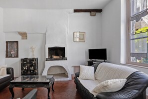 Ein Wohnzimmer mit Kamin, einer Couch, einem Fernseher und einem Schrank.