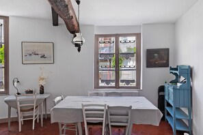 A dining area with a table set for four, a chair, a vase with flowers, and a painting on the wall. - Unique Character House in Beaugency with Wi-Fi (Beaugency)