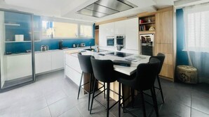 A modern kitchen with a central island, bar stools, and built-in appliances. - Villa Exclusive 10pers, Garages, 10 min Cathedral (Strasbourg)