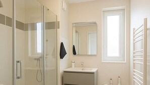 A modern bathroom with a glass shower enclosure, a sink with a mirror, and a towel rack. - Nid des Étoiles, garden, 5 min Strasbourg (Oberhausbergen)