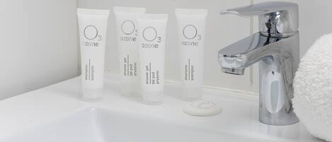 A bathroom sink with four Ozone shampoo tubes, a soap dish, and a chrome faucet.