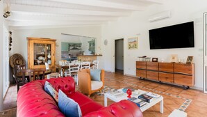 A living room with a red sofa, a dining area with a wooden cabinet, and a kitchen in the background. - Holiday Home 'Tenuta Lu Mimmu' with Private Terrace, Wi-Fi and Air Conditioning (Matino)