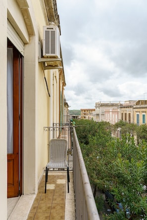 A balcony with a chair, a door, and an air conditioning unit.