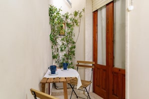A small wooden table with two chairs, a potted plant, and a framed picture on the wall.