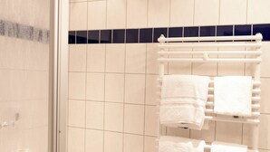 A bathroom with a toilet, a sink, and a towel rack with multiple white towels. - Hotel Eifeltor (Mechernich)