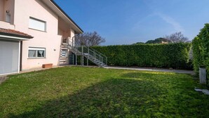 A two-story house with a staircase leading to a balcony, a well-maintained lawn, and a hedge in the background. - A comfortable and bright 40 sq m studio apartment, perfect for two people, located on the first floor of a small villa (no elevator).The property is located in an extremely quiet area surrounded by greenery, with a cycle path nearby. Guests can easily re (Udine)
