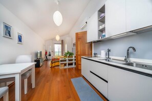 Une cuisine moderne avec des meubles blancs, un évier en acier inoxydable et une table à manger en bois.