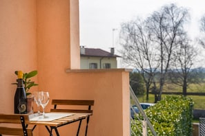 Ein Balkon mit Tisch, einer Flasche und zwei Gläsern.