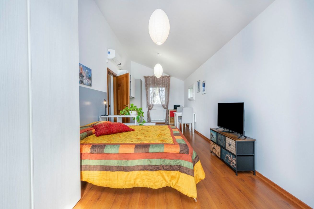 Ein Schlafzimmer mit einem Bett, einem Fernseher, einem Schreibtisch und einem Sessel.