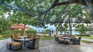 An outdoor patio with wicker furniture, a table, and a view of a body of water. - Isla Mujeres | Relaxing Island Retreat | Pool + Beach (Isla Mujeres)