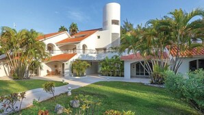 A modern hotel with a central courtyard, palm trees, and a distinctive cylindrical tower. - Isla Mujeres | Relaxing Island Retreat | Pool + Beach (Isla Mujeres)