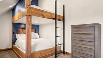A bunk bed with a wooden frame and a ladder, a dresser with drawers, and a blue accent wall.