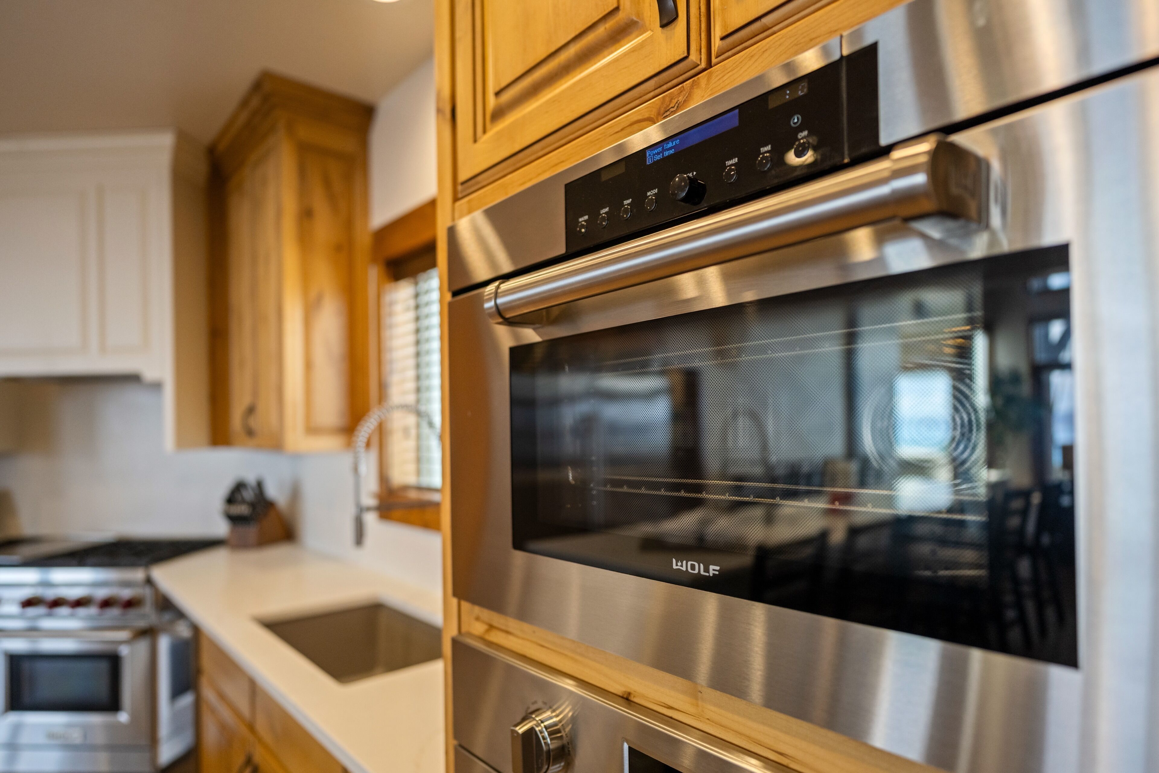 A kitchen with stainless steel appliances, wooden cabinets, and a built-in oven.
