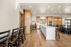 A spacious kitchen with wooden cabinets, a central island, and a dining area with chairs.